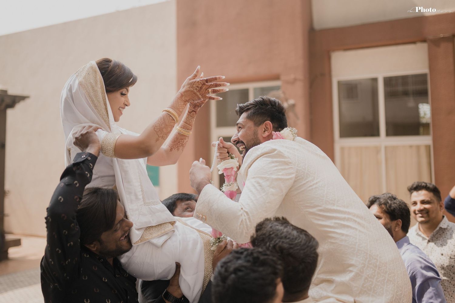 Wedding guests lift and celebrate during a joyous moment at an outdoor celebration.