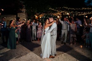 A romantic first dance moment under twinkling lights at an evening wedding reception.