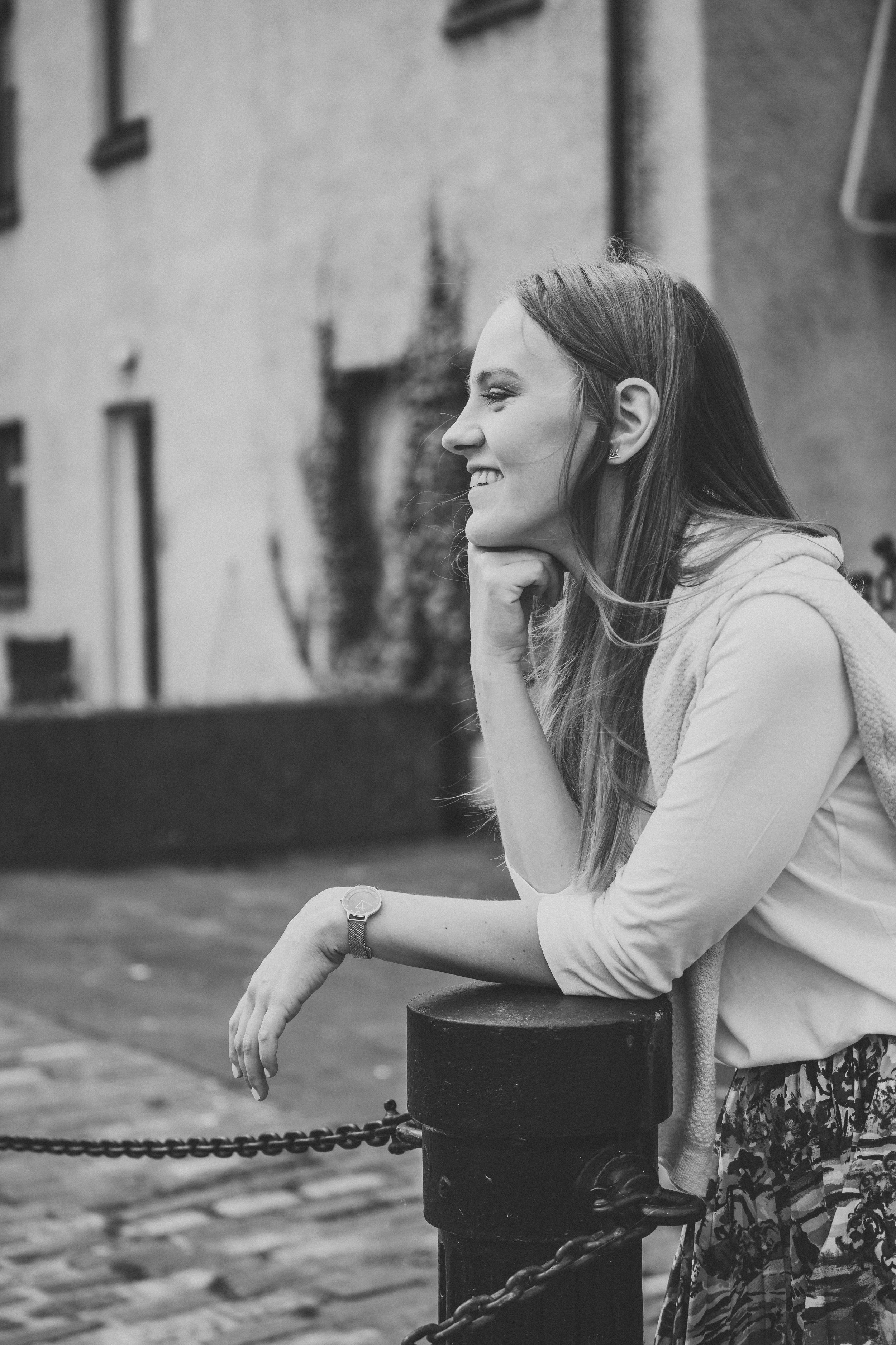 Black and white portrait of person leaning on railing in contemplative pose.