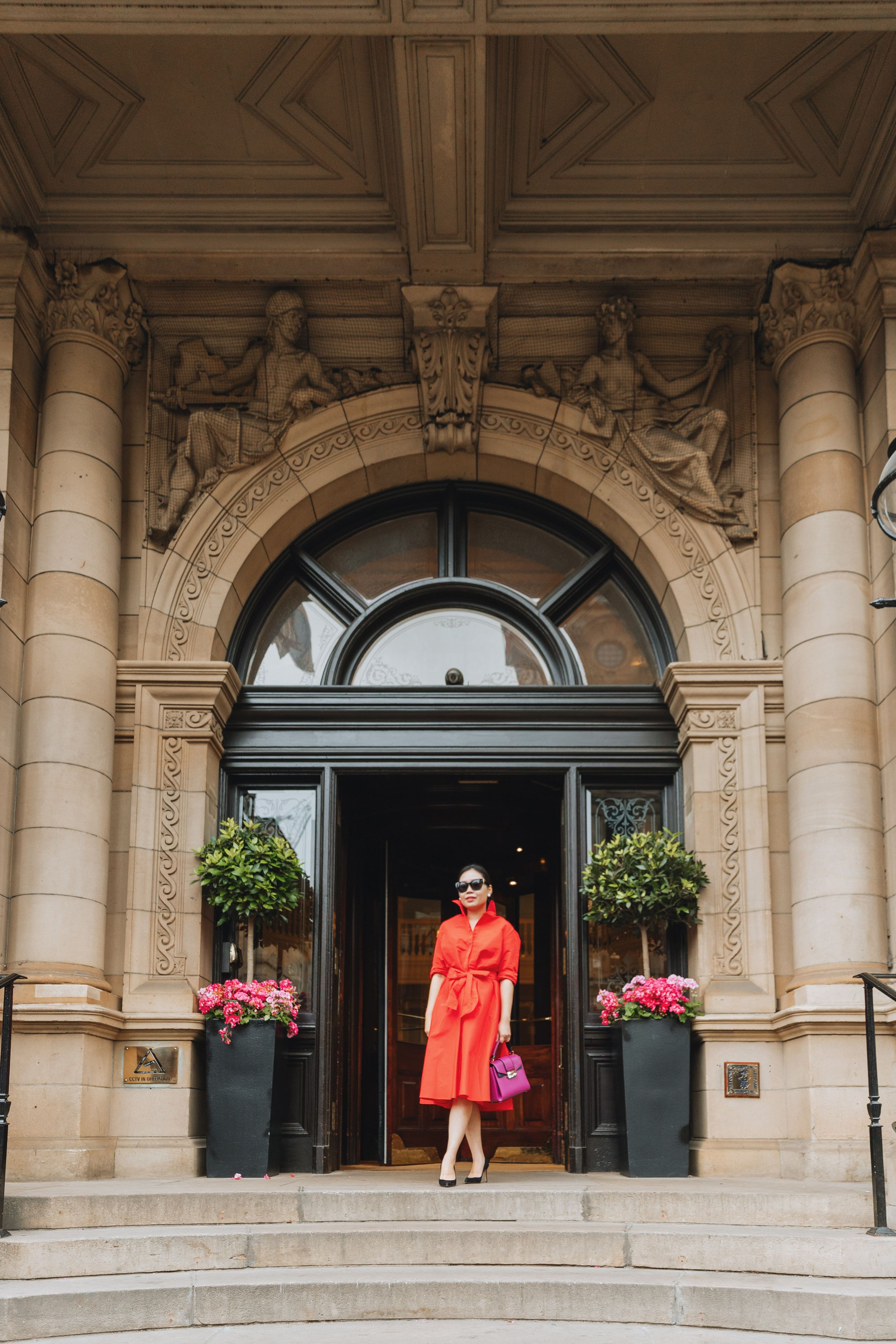 Elegant architectural entrance with ornate stonework and potted flowers framing doorway.