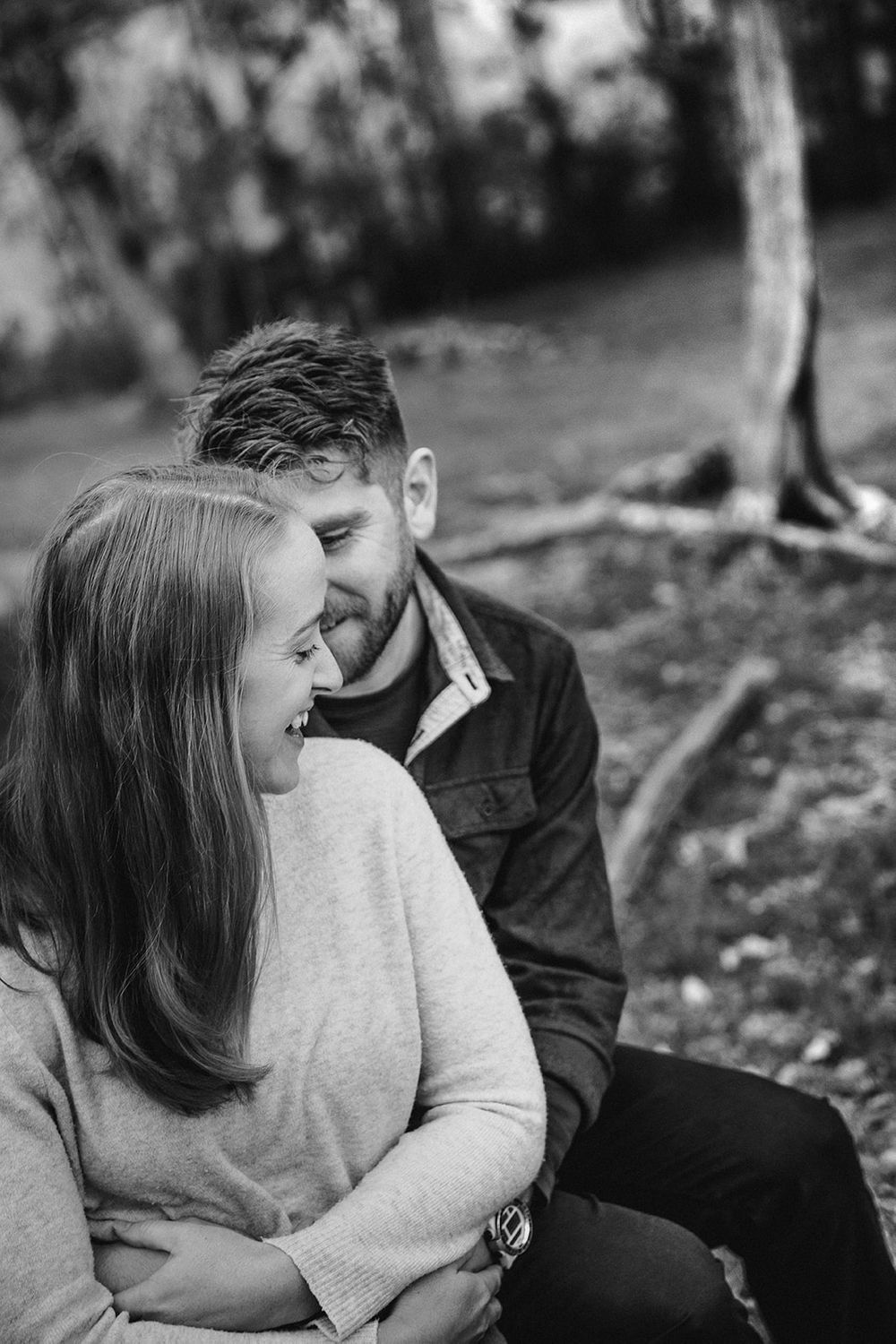 An intimate black and white portrait of a couple sharing a tender moment outdoors.