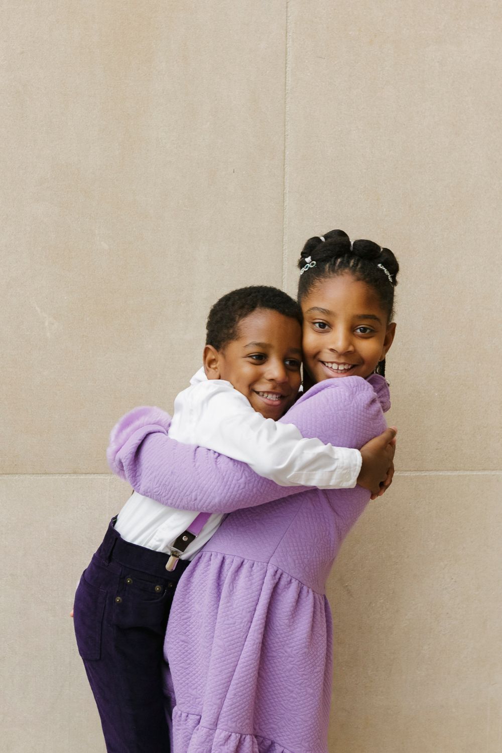 Siblings sharing a joyous embrace, radiating warmth and happiness in a heartwarming moment captured by Paula Ortiz