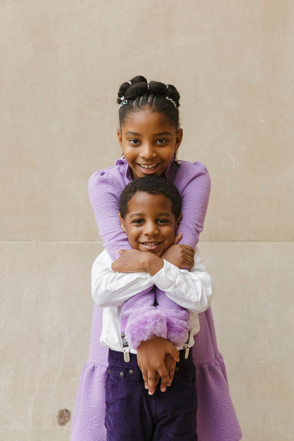 Siblings exuding happiness in a delightful embrace, their genuine smiles shining through by NYC family photographer