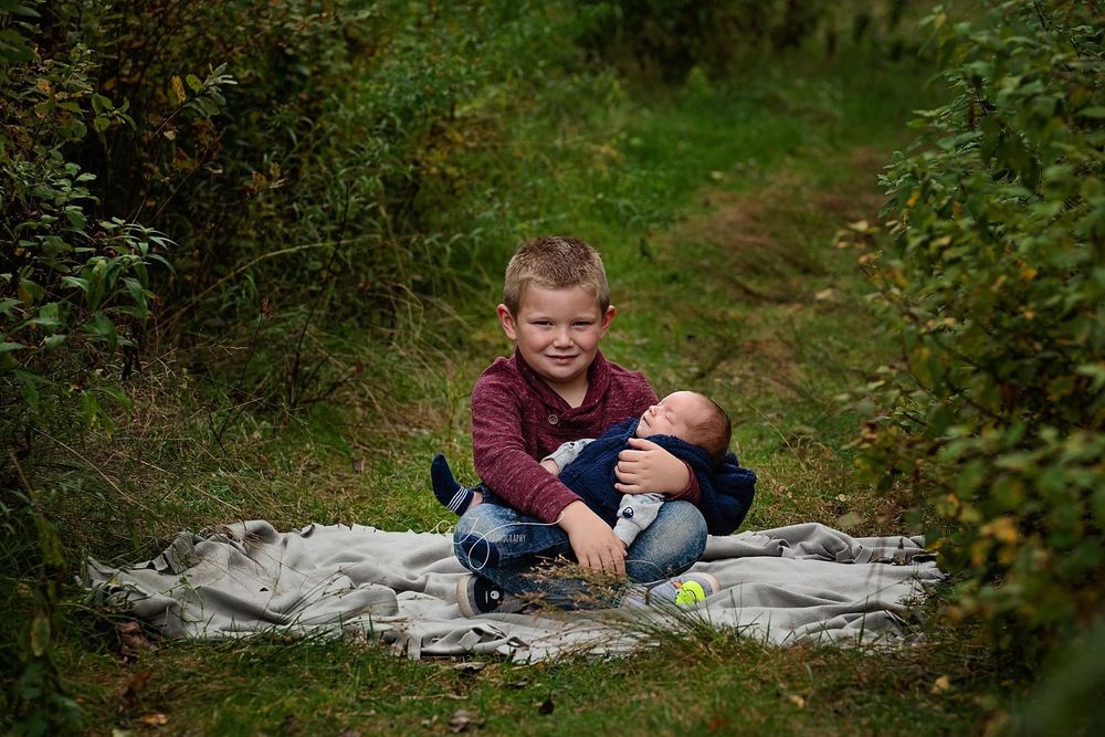 Child sitting on blanket in outdoor garden setting during portrait session.