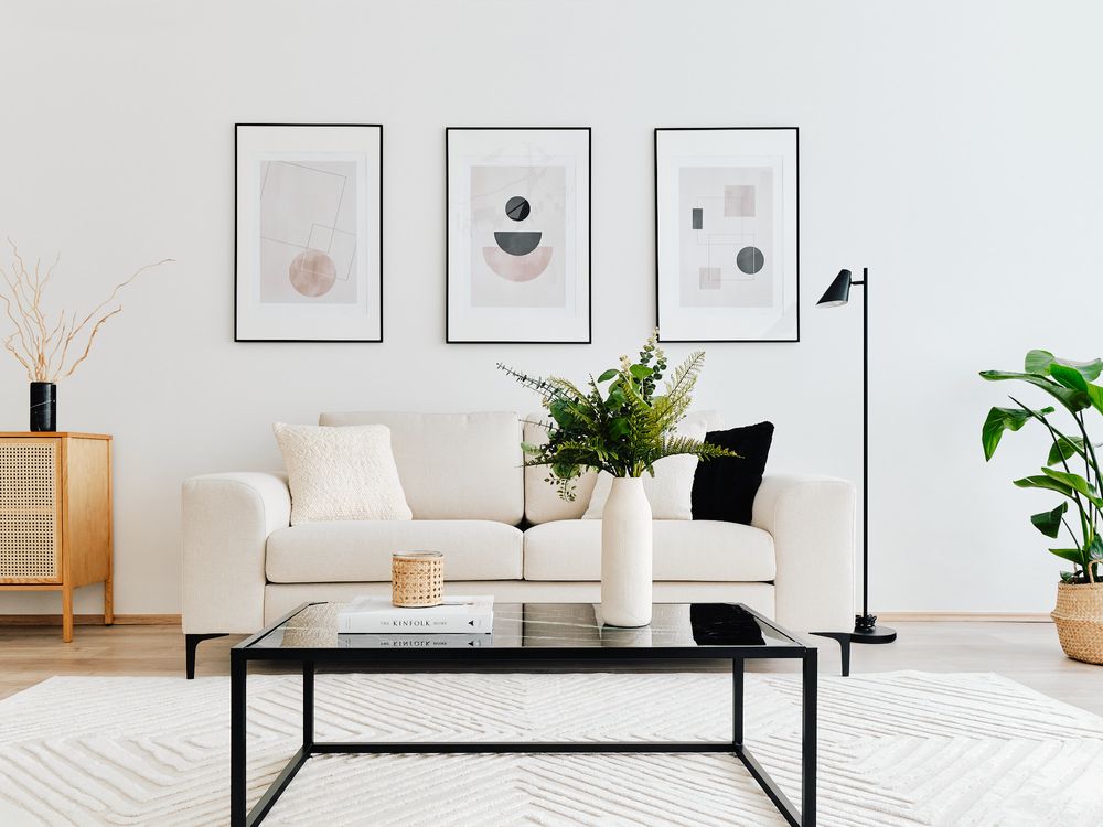 Minimalist living room with geometric artwork, black coffee table, and indoor plants.