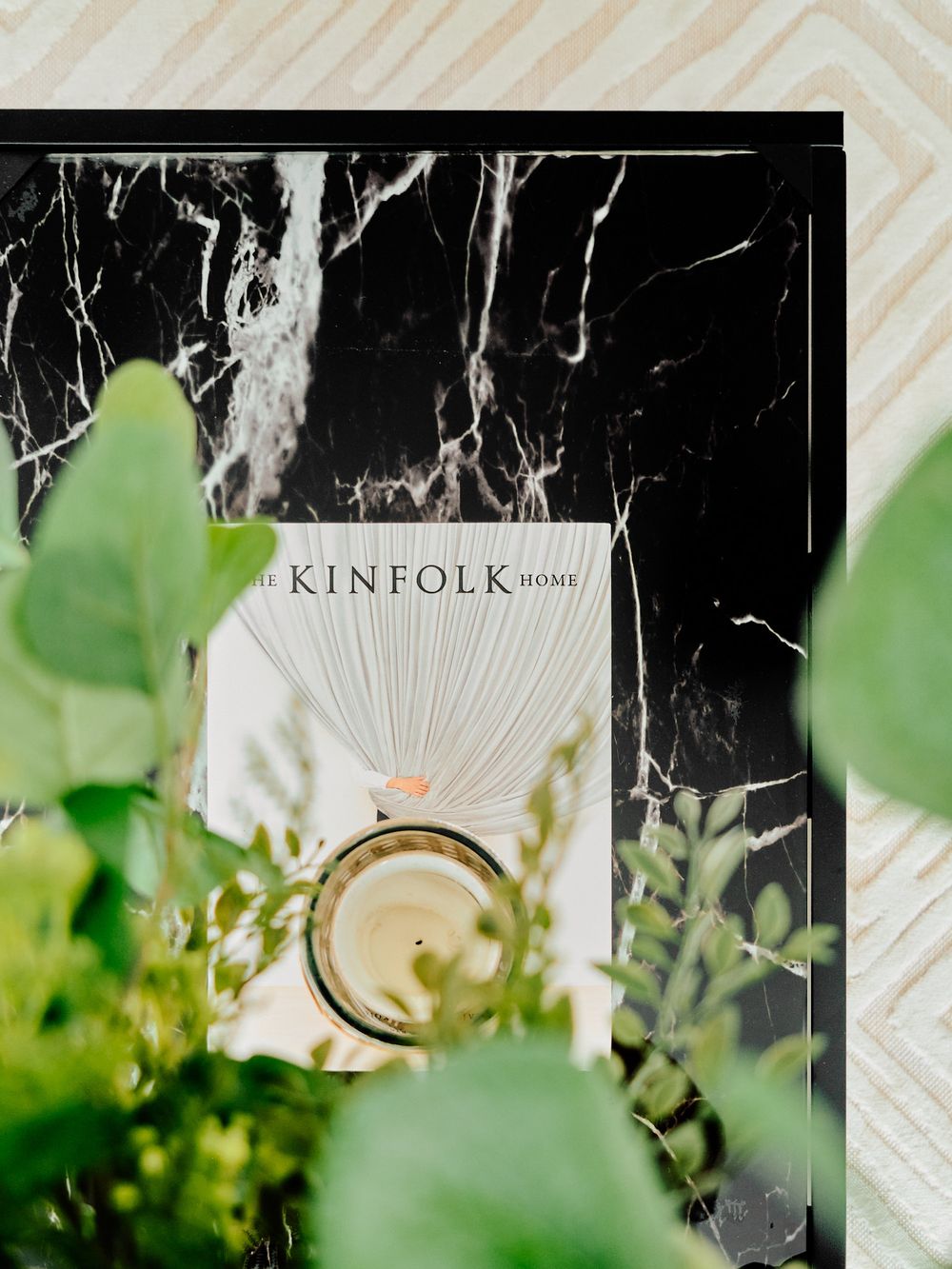 Kinfolk magazine on black marble surface with green plants in soft focus.