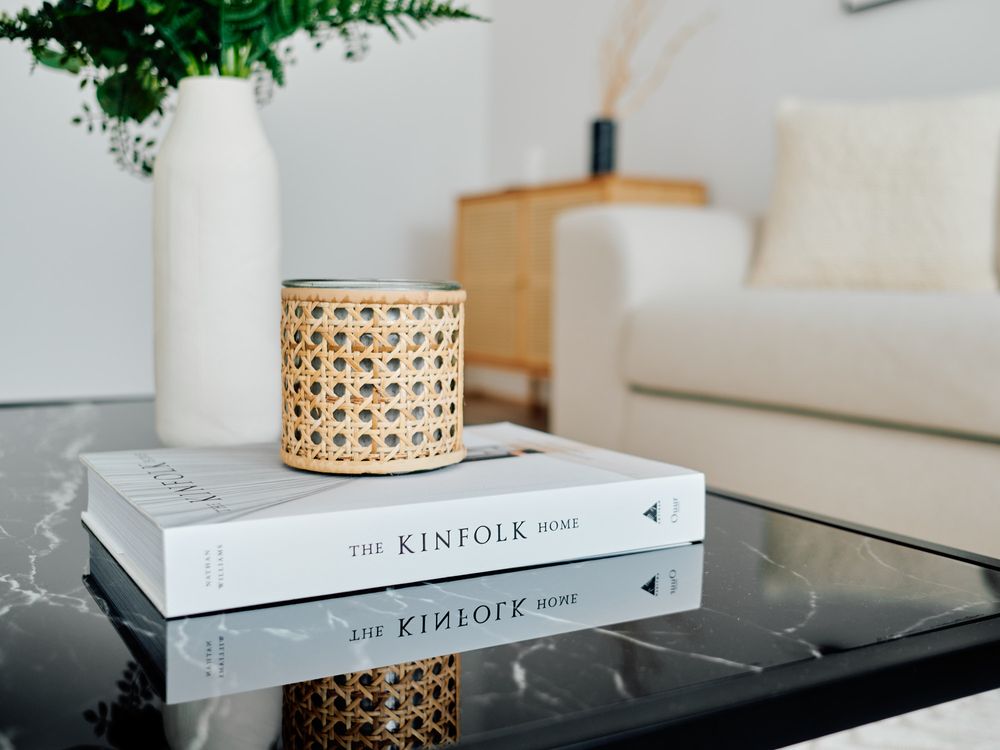 Rattan candle holder on stacked Kinfolk books with marble table surface.