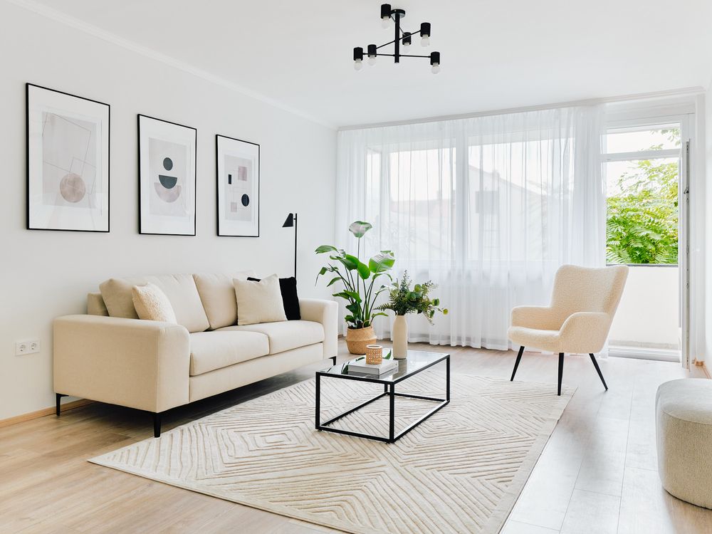 Modern minimalist living room with beige sofa, abstract wall art, and geometric rug.