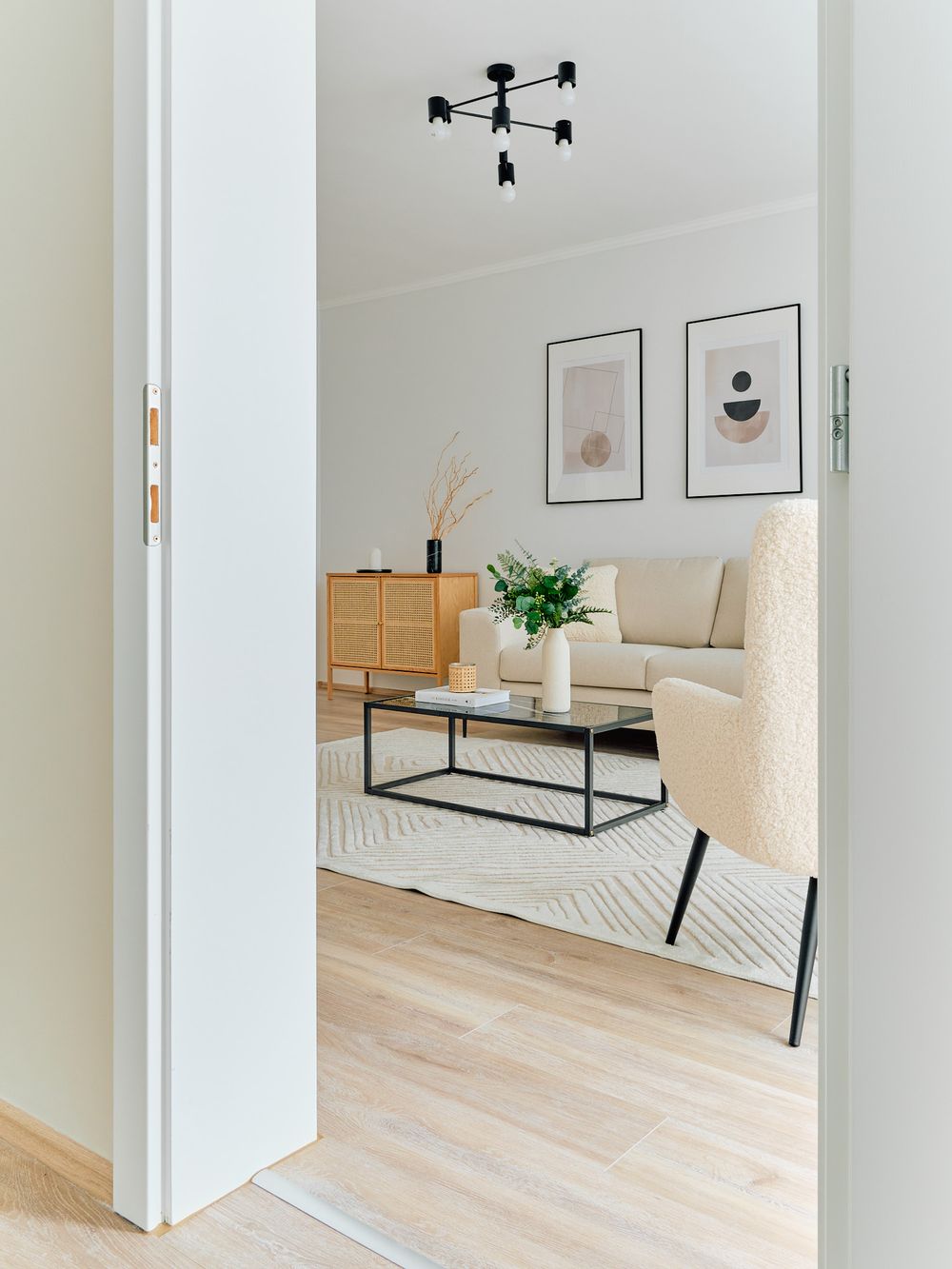 Bright Scandinavian living room interior with beige sofa and geometric light fixture.