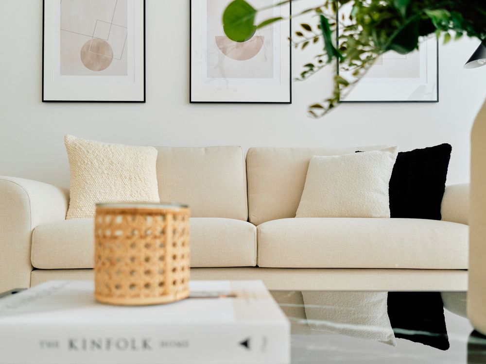 Cozy living room corner with cream sofa, abstract prints, and woven basket decor.