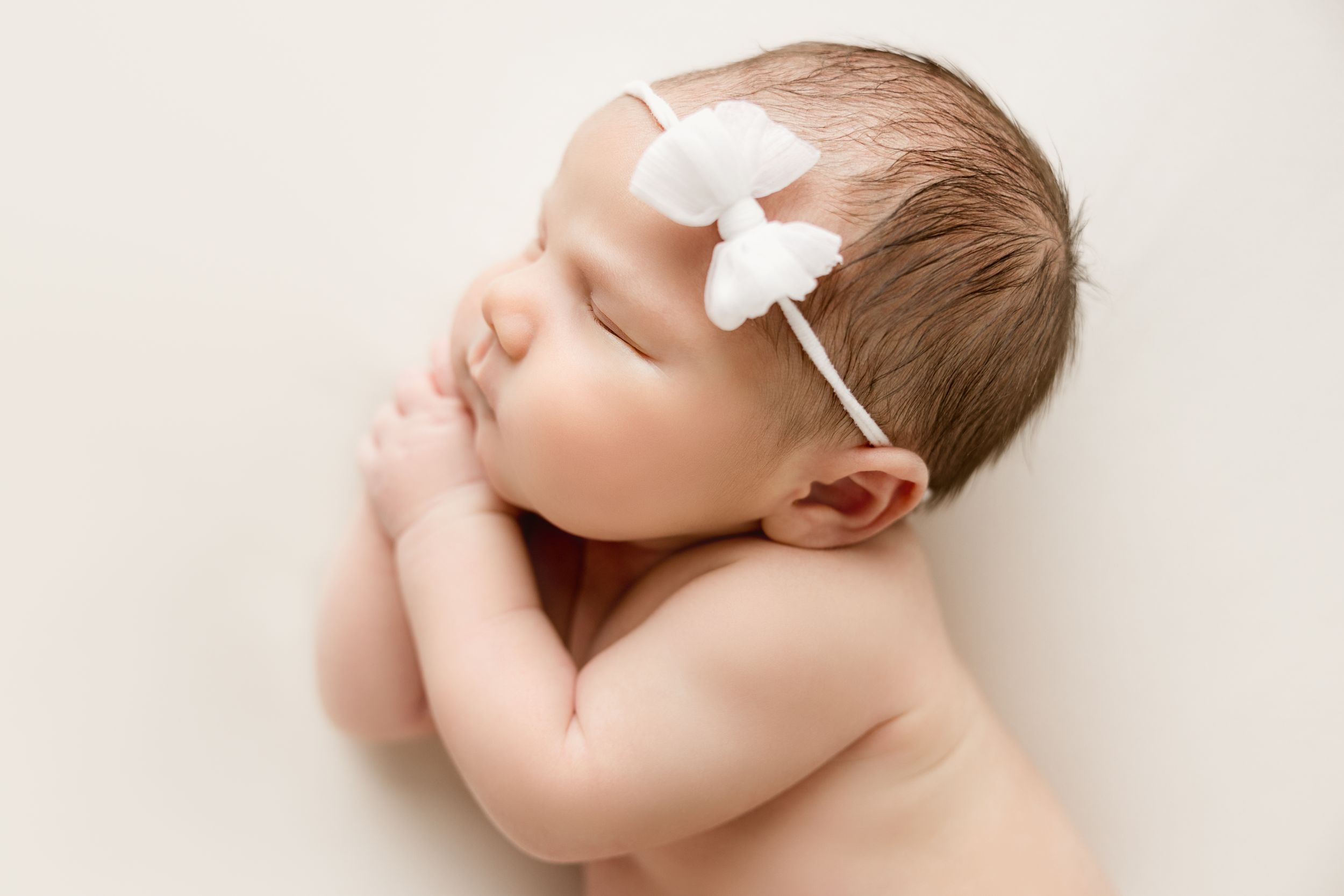 Sweet and simple newborn photograph. Newborn baby girl with a white bow.