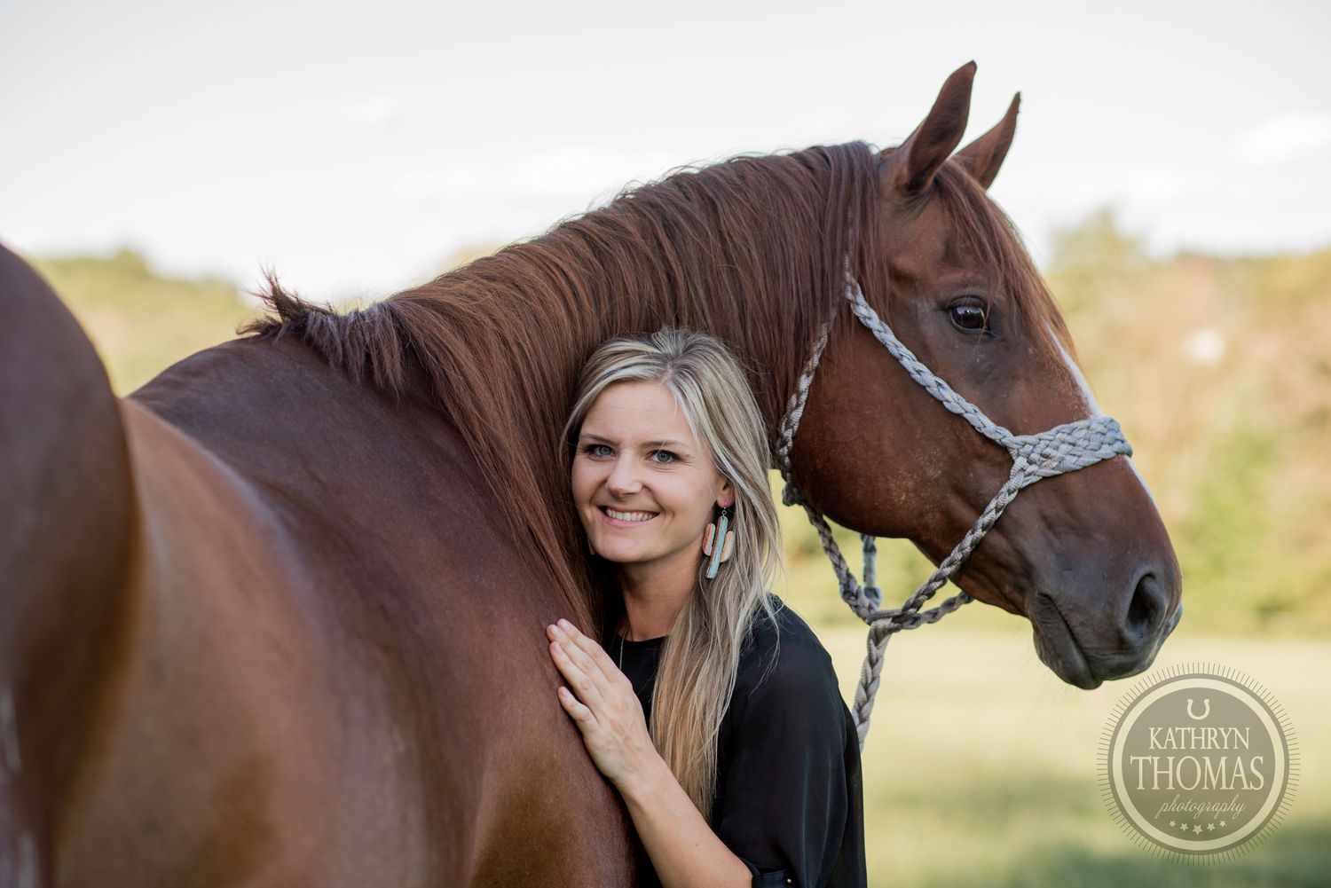 Brown horse with dark mane poses with companion against natural outdoor backdrop.