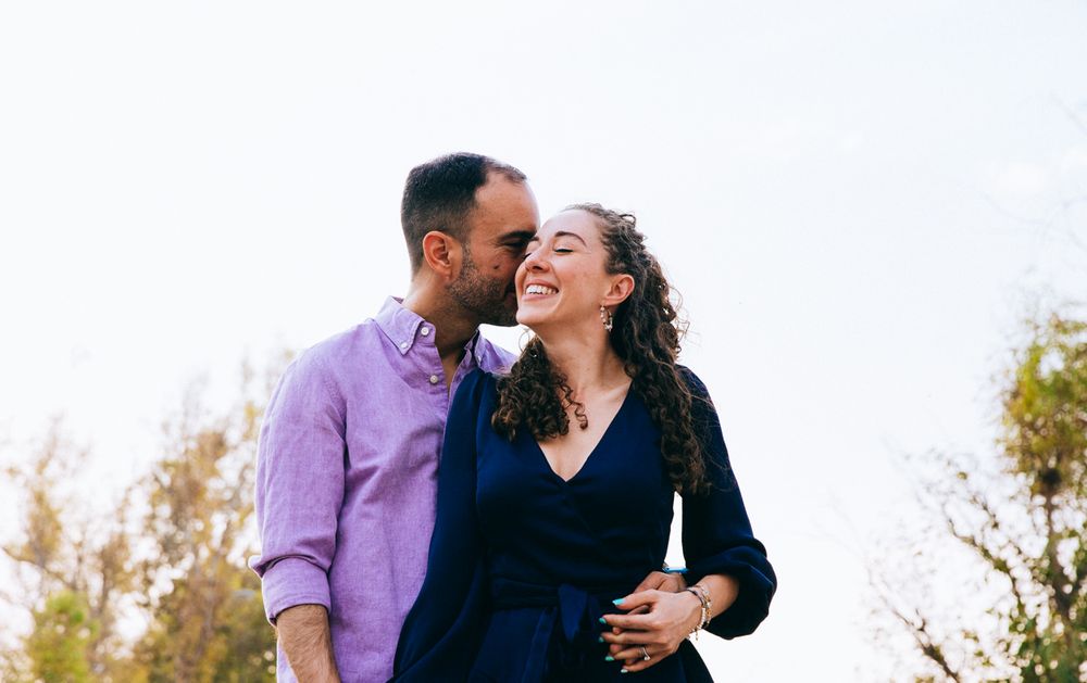 Happy couple embracing and laughing together outdoors in casual attire.