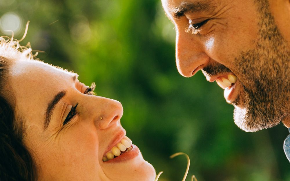 Close-up of two people sharing a tender moment against a blurred green background.