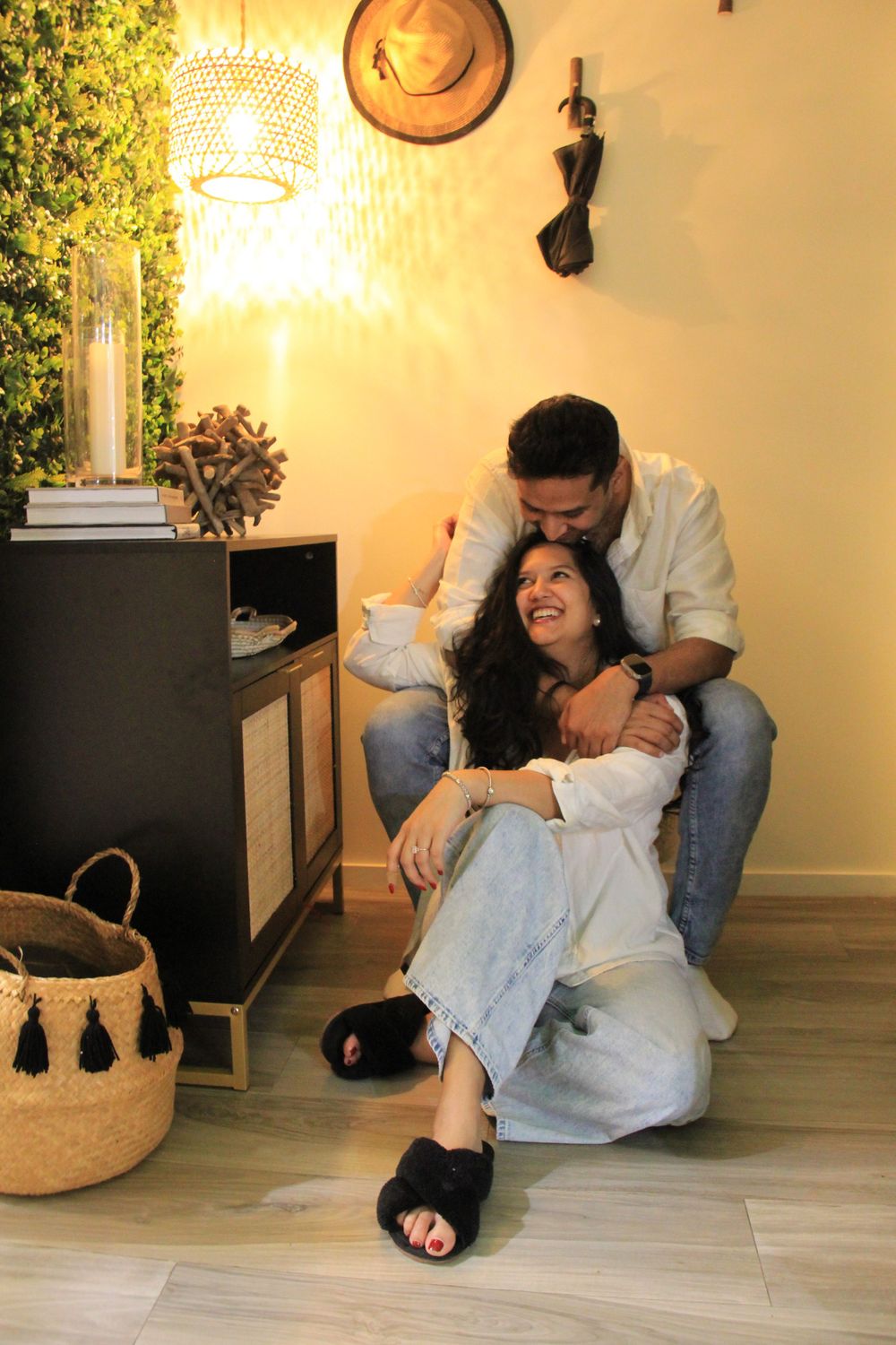 Intimate moment captured between couple sitting on floor with warm lighting and home decor.