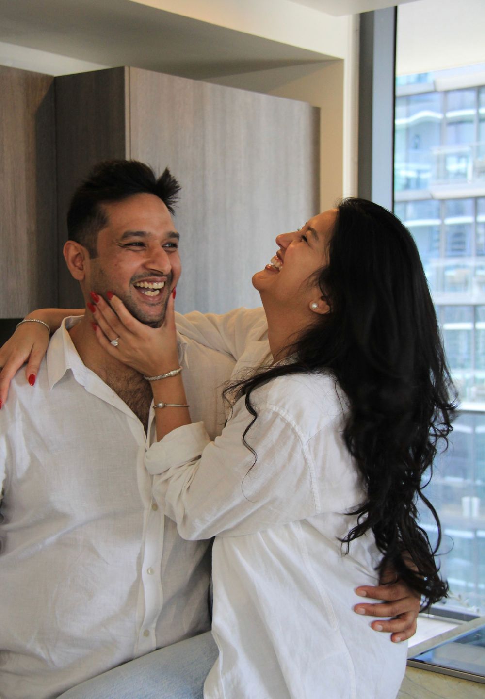 Candid photo of a couple in matching white shirts sharing a joyful moment in a modern apartment in Miami, FL.