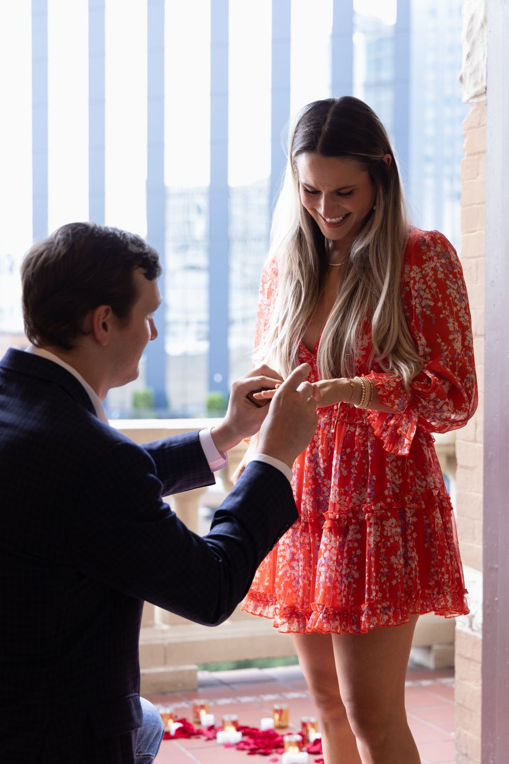 A romantic proposal scene with a couple in front of a city skyline backdrop.
