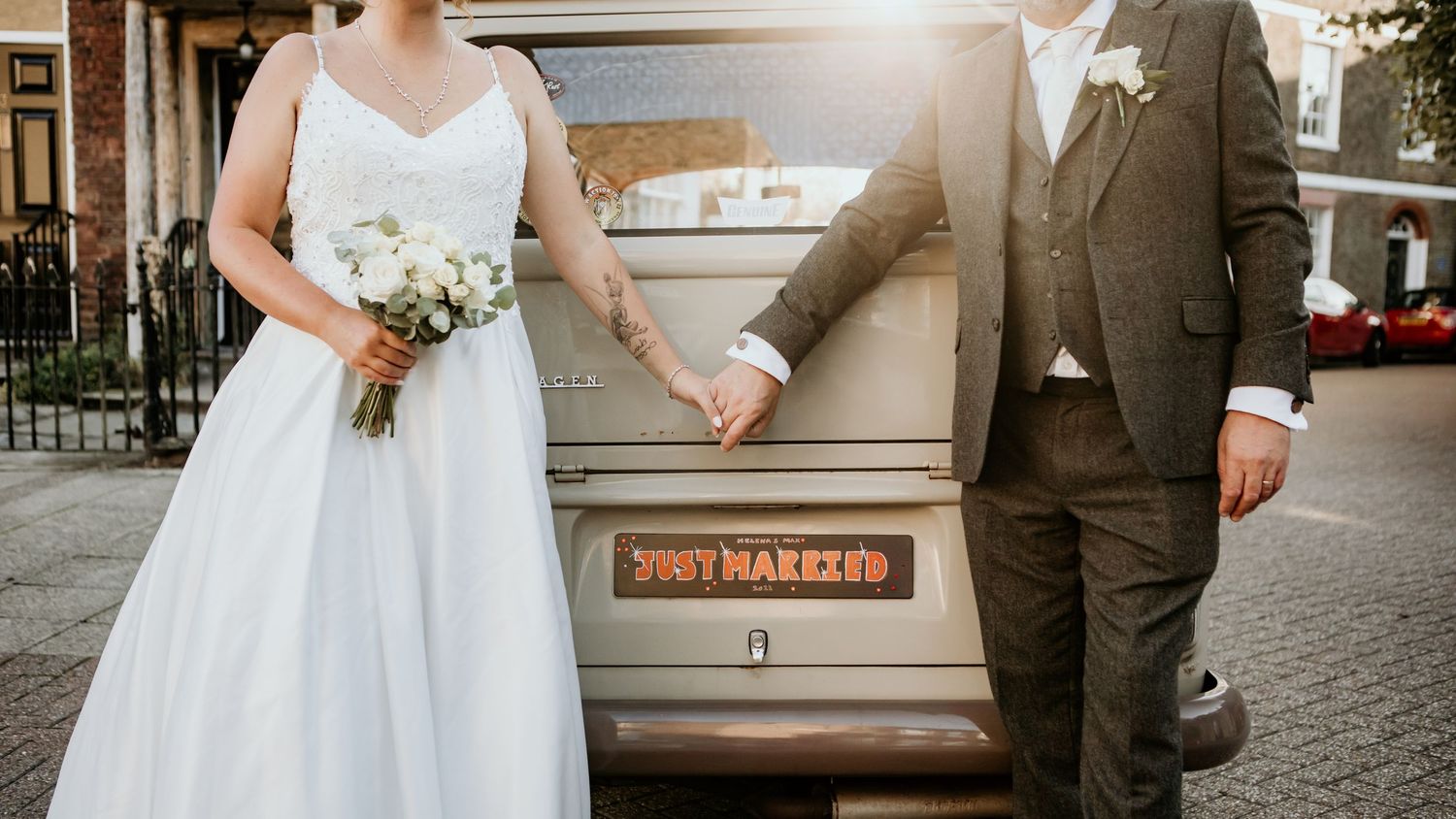 couple in front of minivan holding hands with sun in window