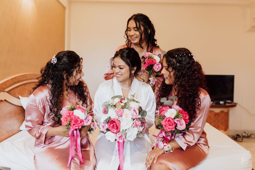 Bridesmaids in matching pink robes holding vibrant pink and white bouquets.