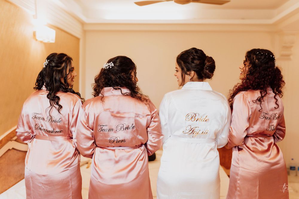 Wedding party wearing coordinated pink satin robes with custom text on the back.