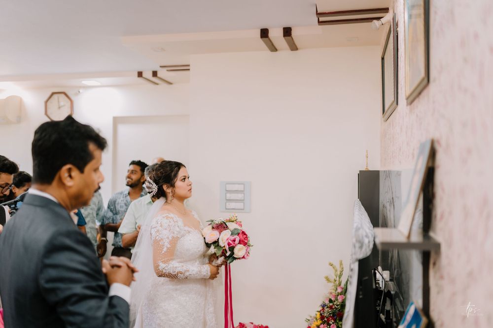 Emotional wedding ceremony moment in a church with bridesmaids in coral dresses looking on.