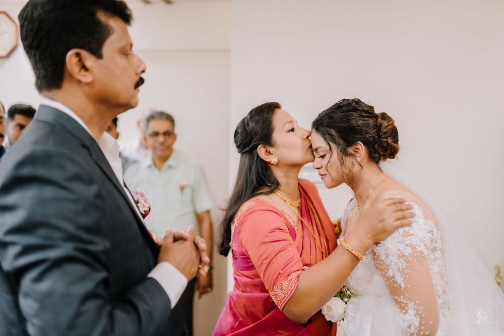 Bridesmaids in coral dresses share emotional reactions during wedding ceremony.