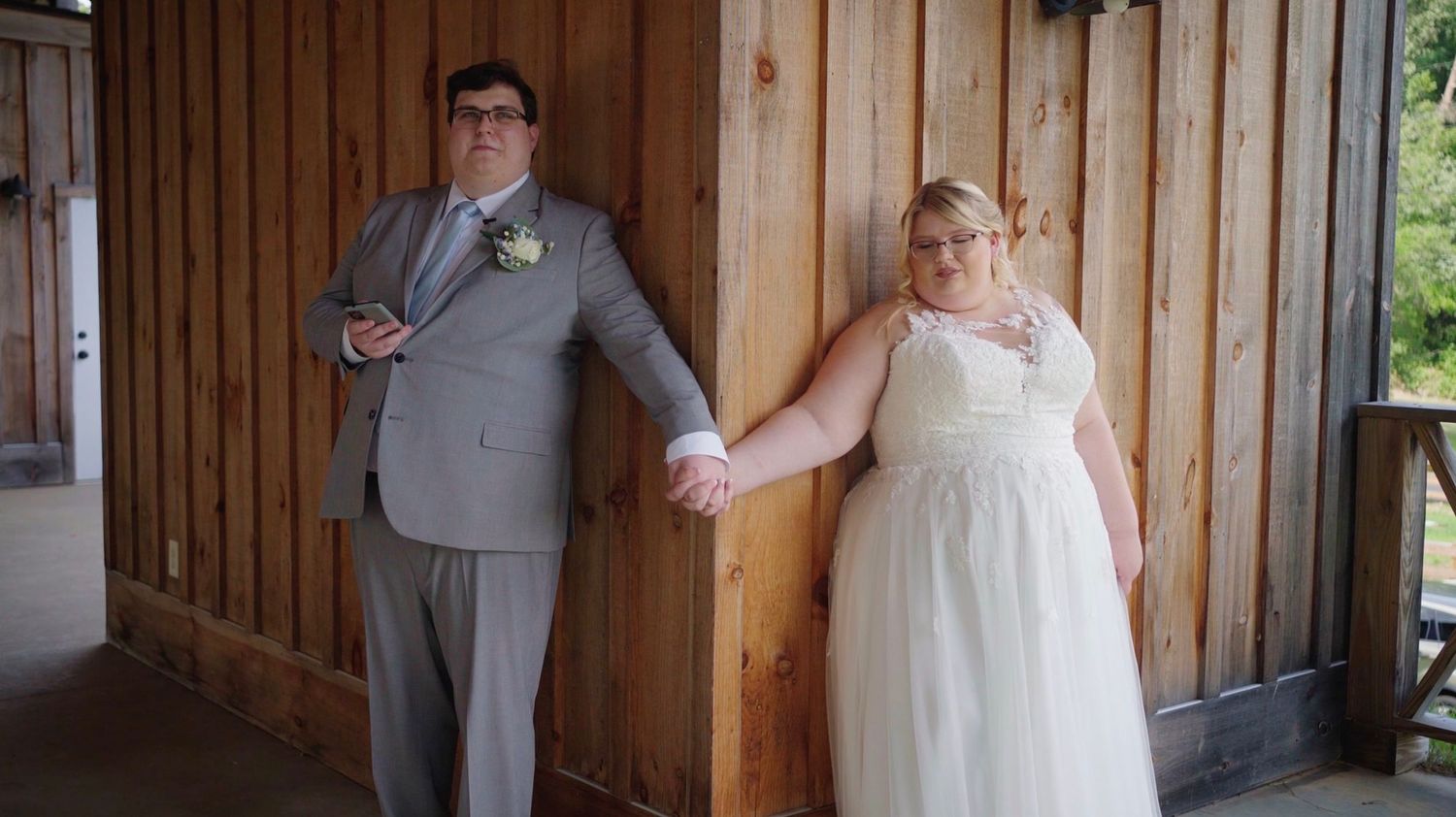 A couple holding hands around a corner so they cannot see each other