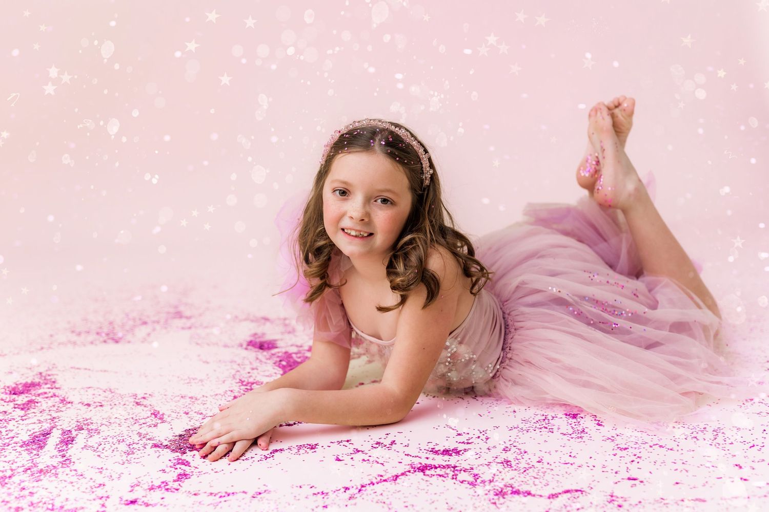 little girl laying down in pink glitter smiling