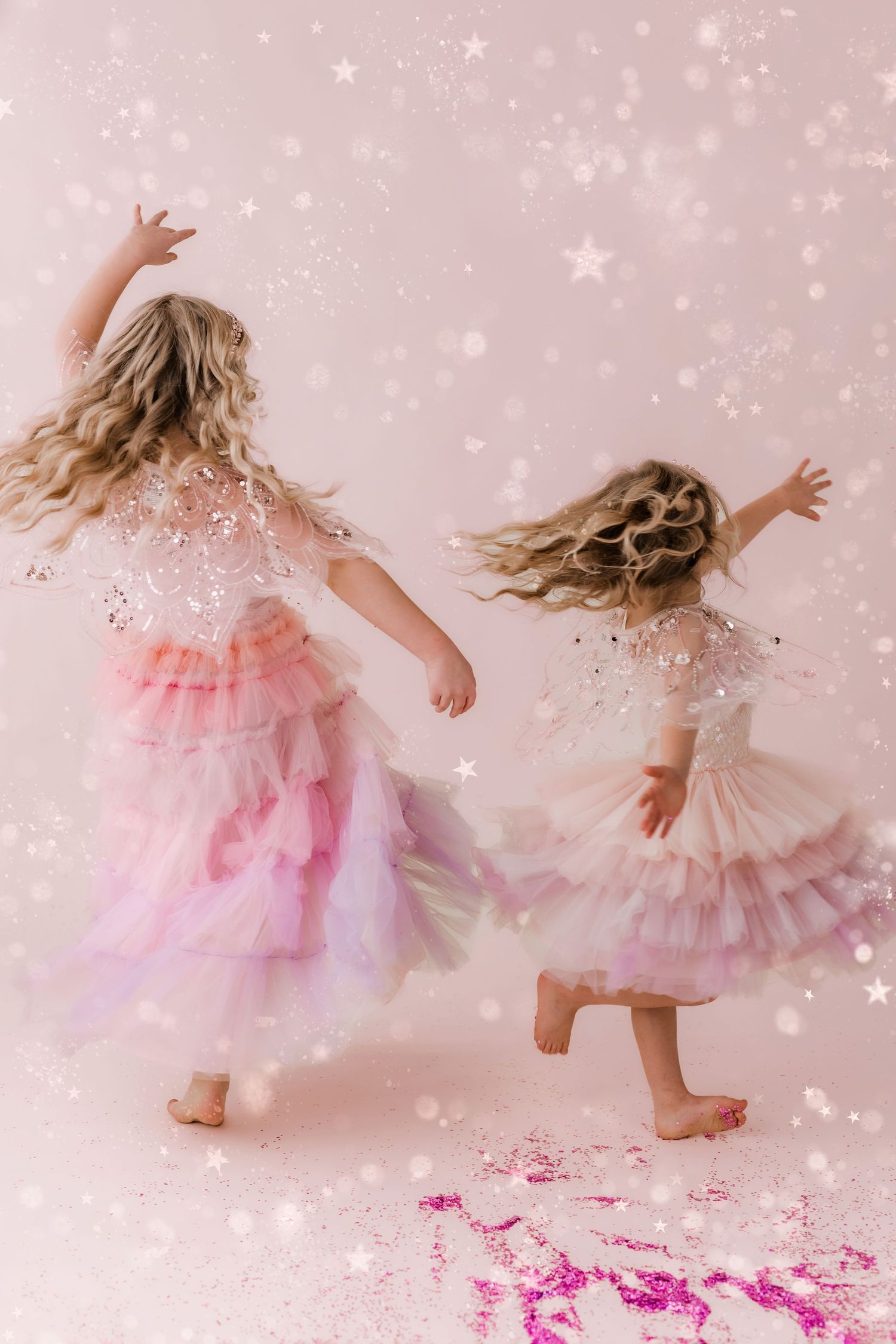 two little girls twirling in bright pink and white glitter