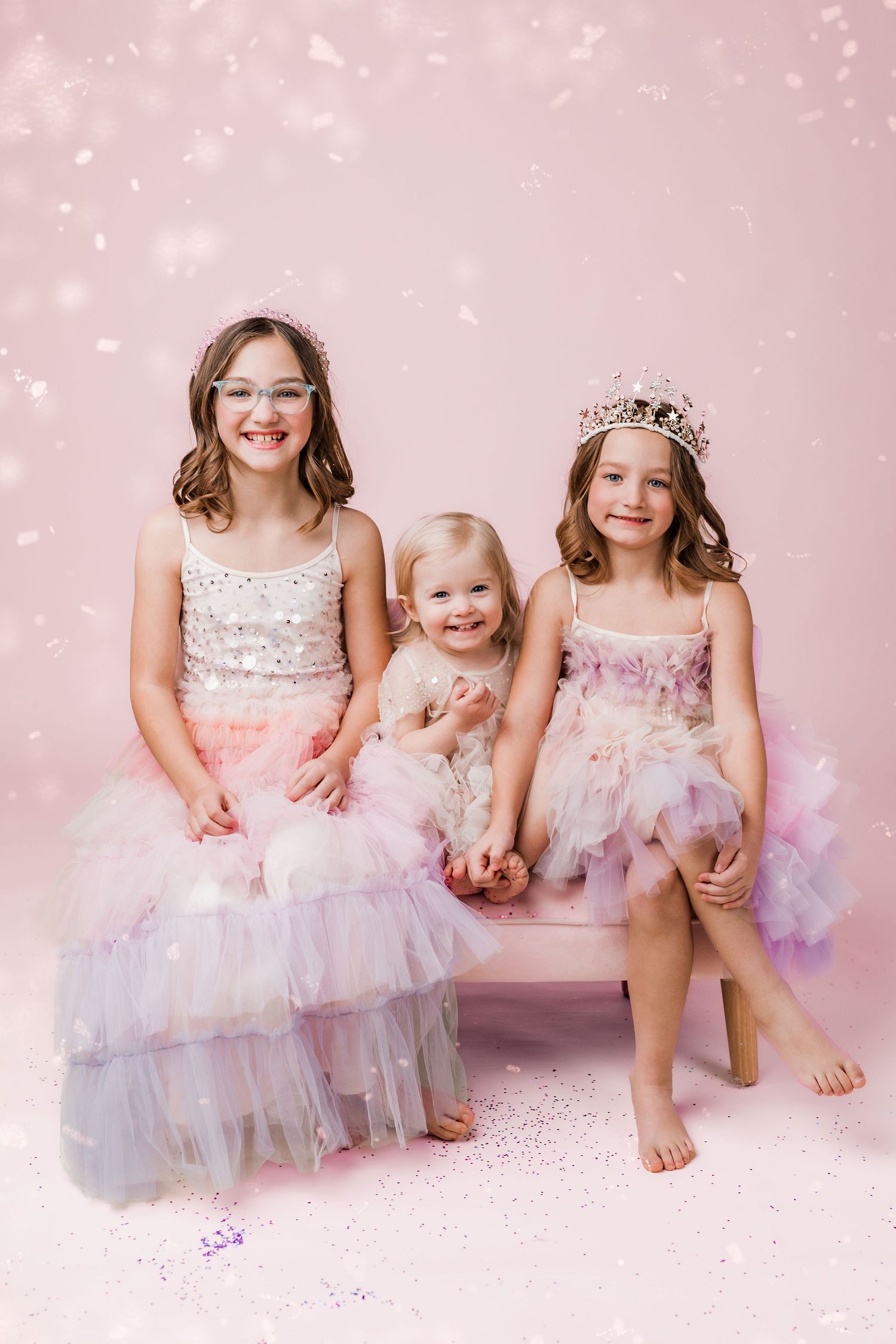 three little girls dressed in dresses and tiaras