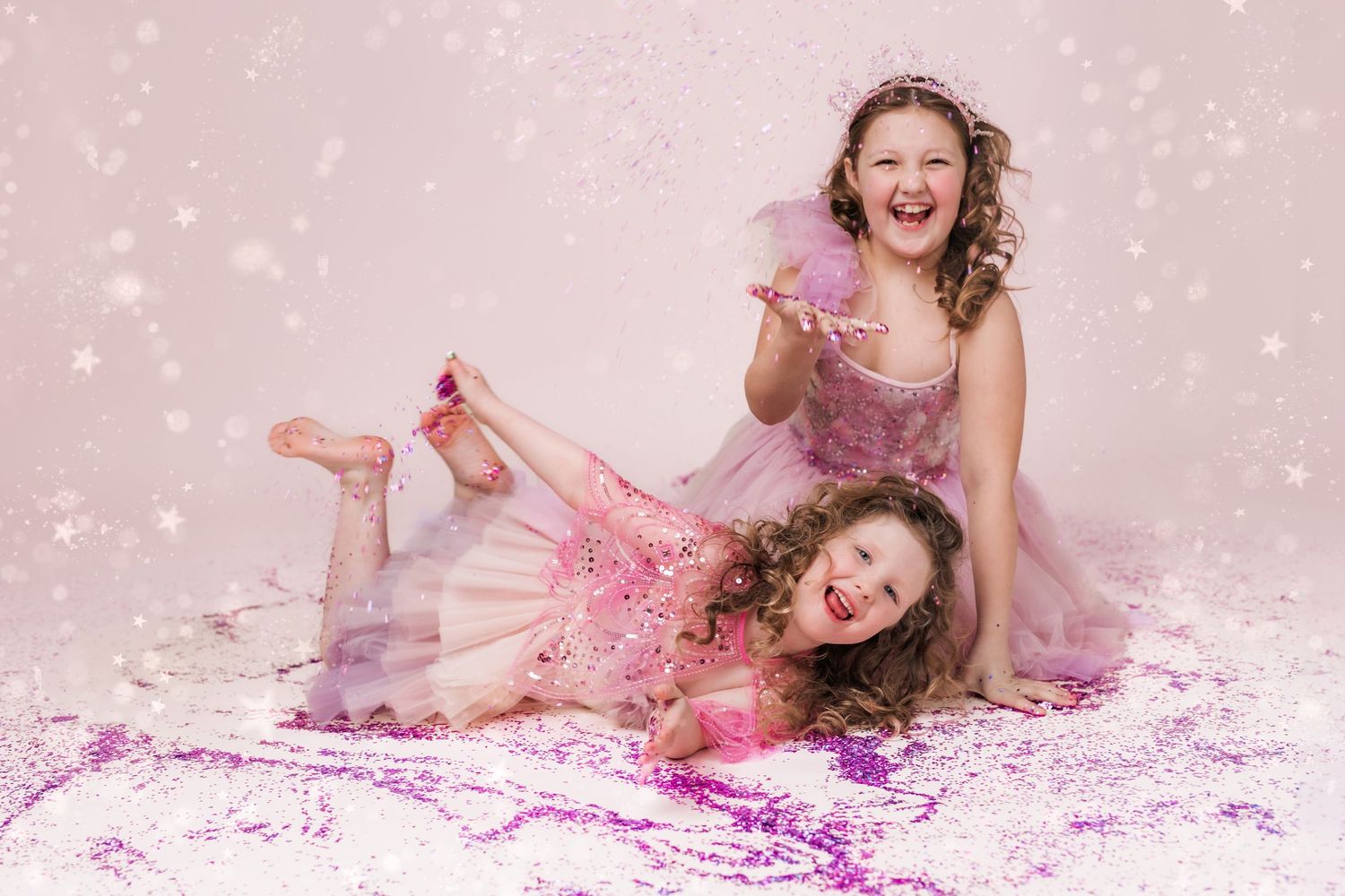 two girls laughing playing with pink glitter