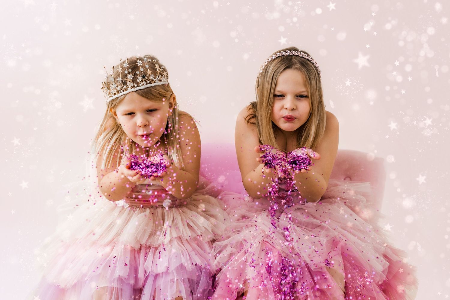 two girls blowing glitter in princess dresses and tiaras