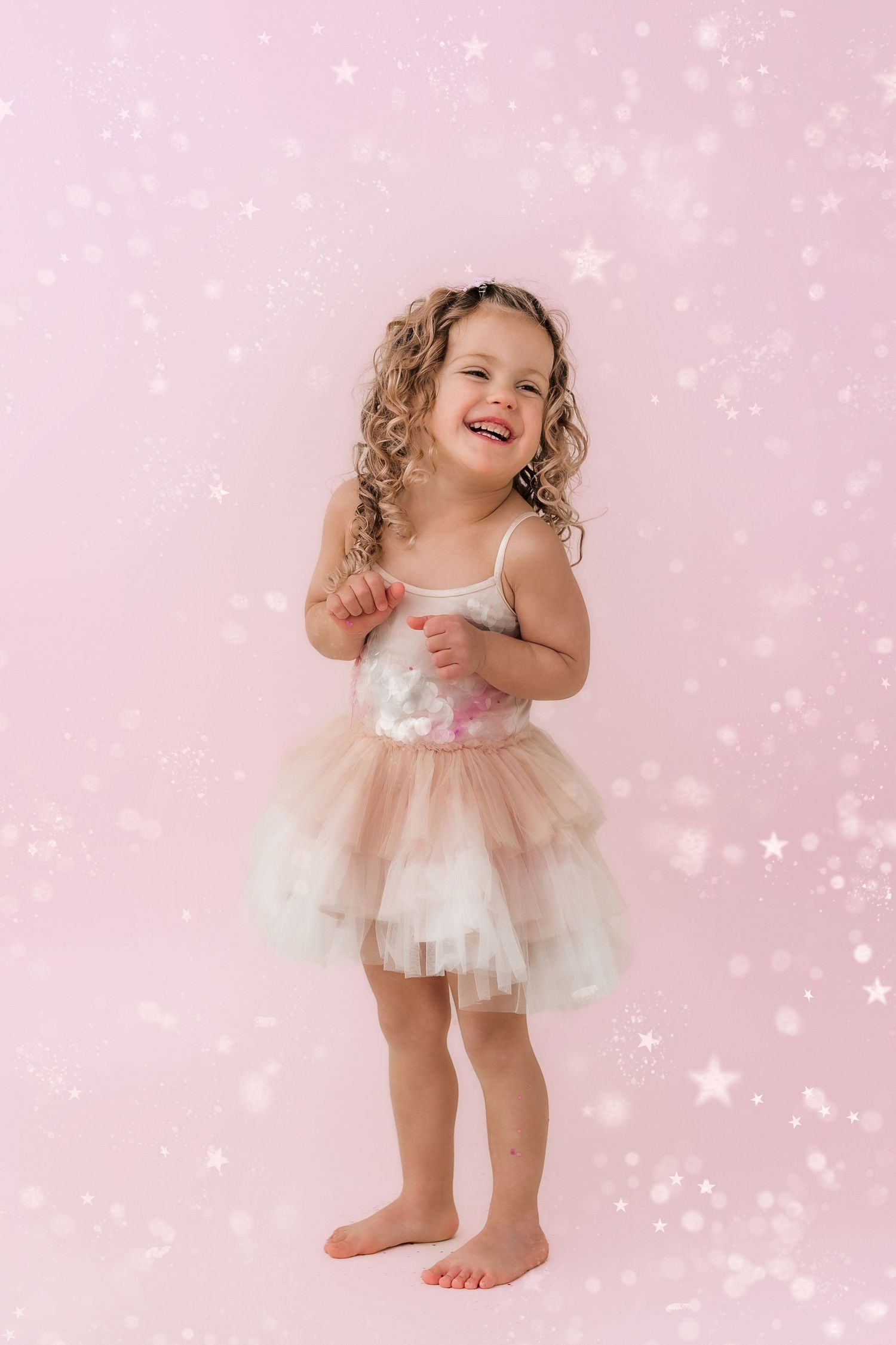 little girl laughing in front of glitter background