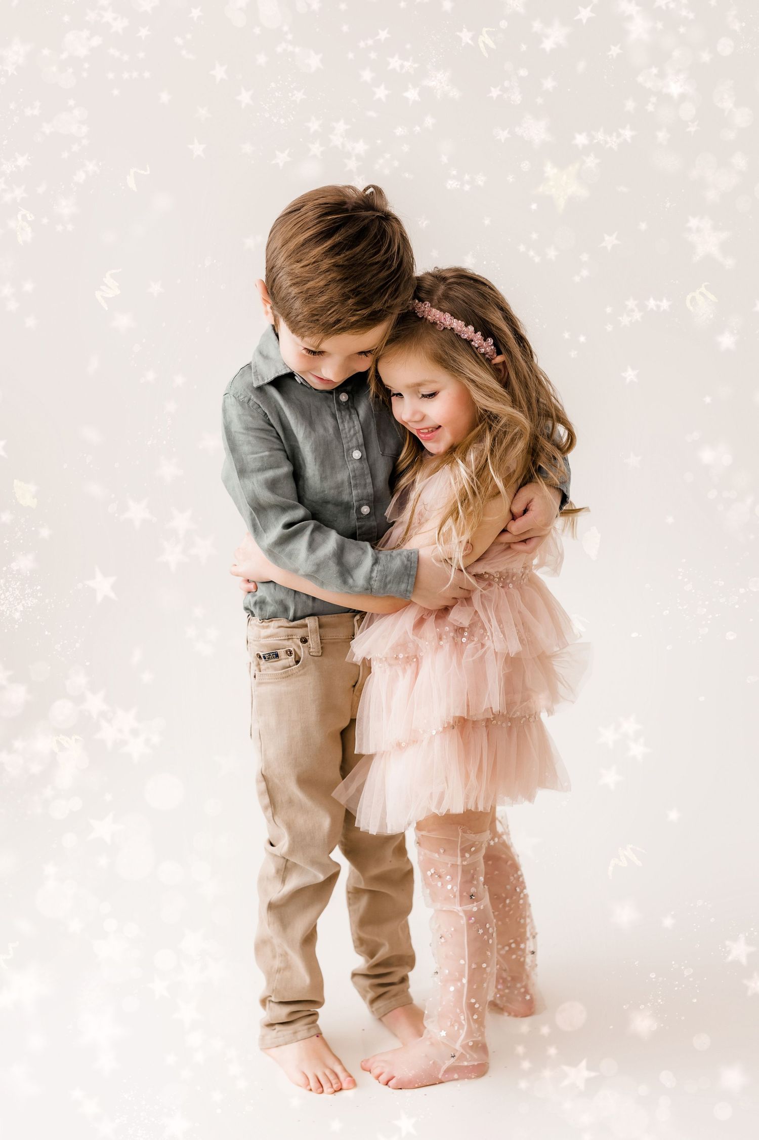 brother and sister hugging in front of a magical glitter background