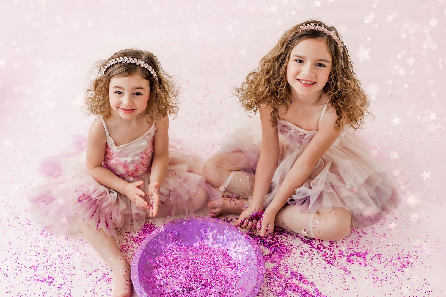 two girls playing with a bowl of pink glitter