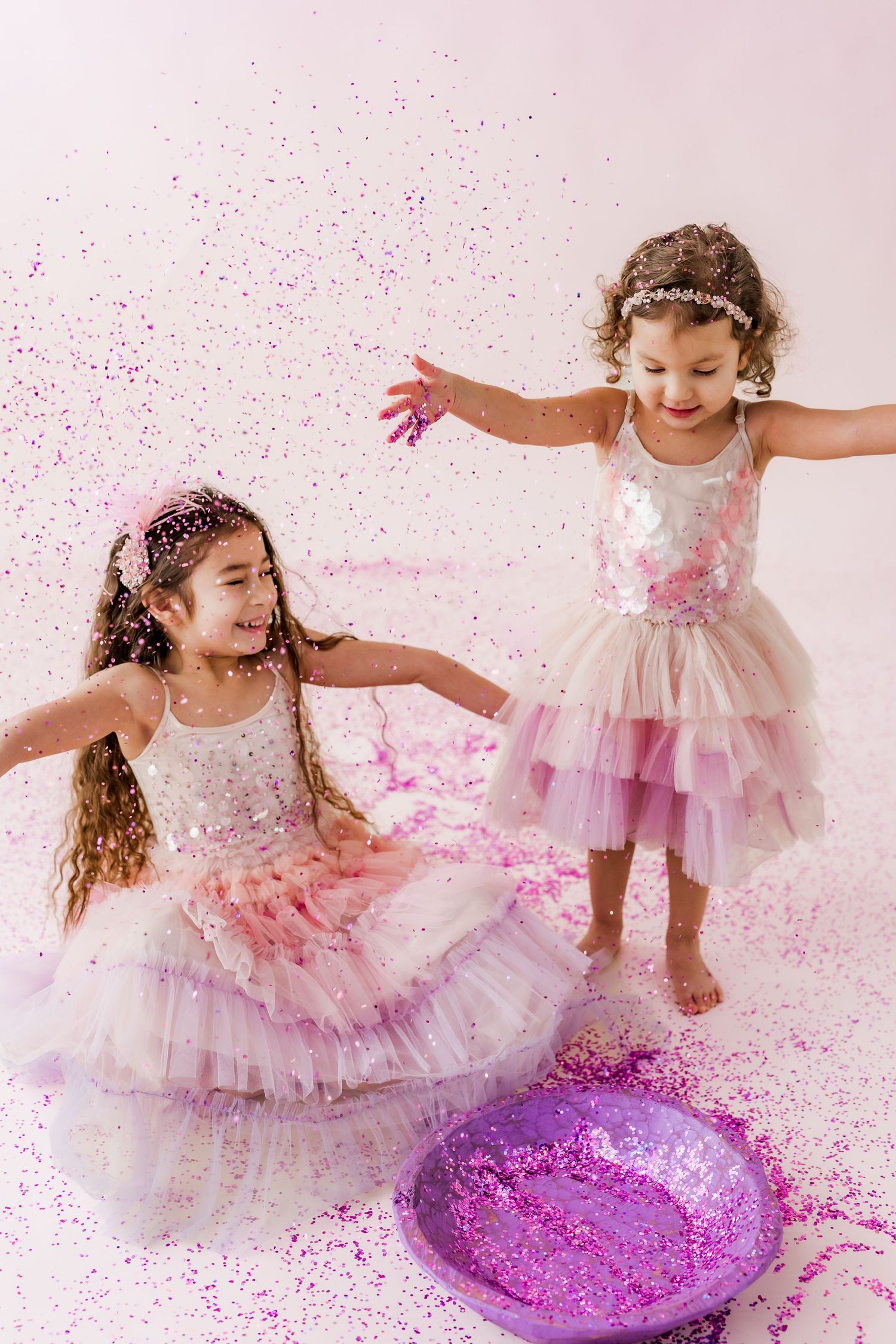 two girls throwing pink glitter and playing together