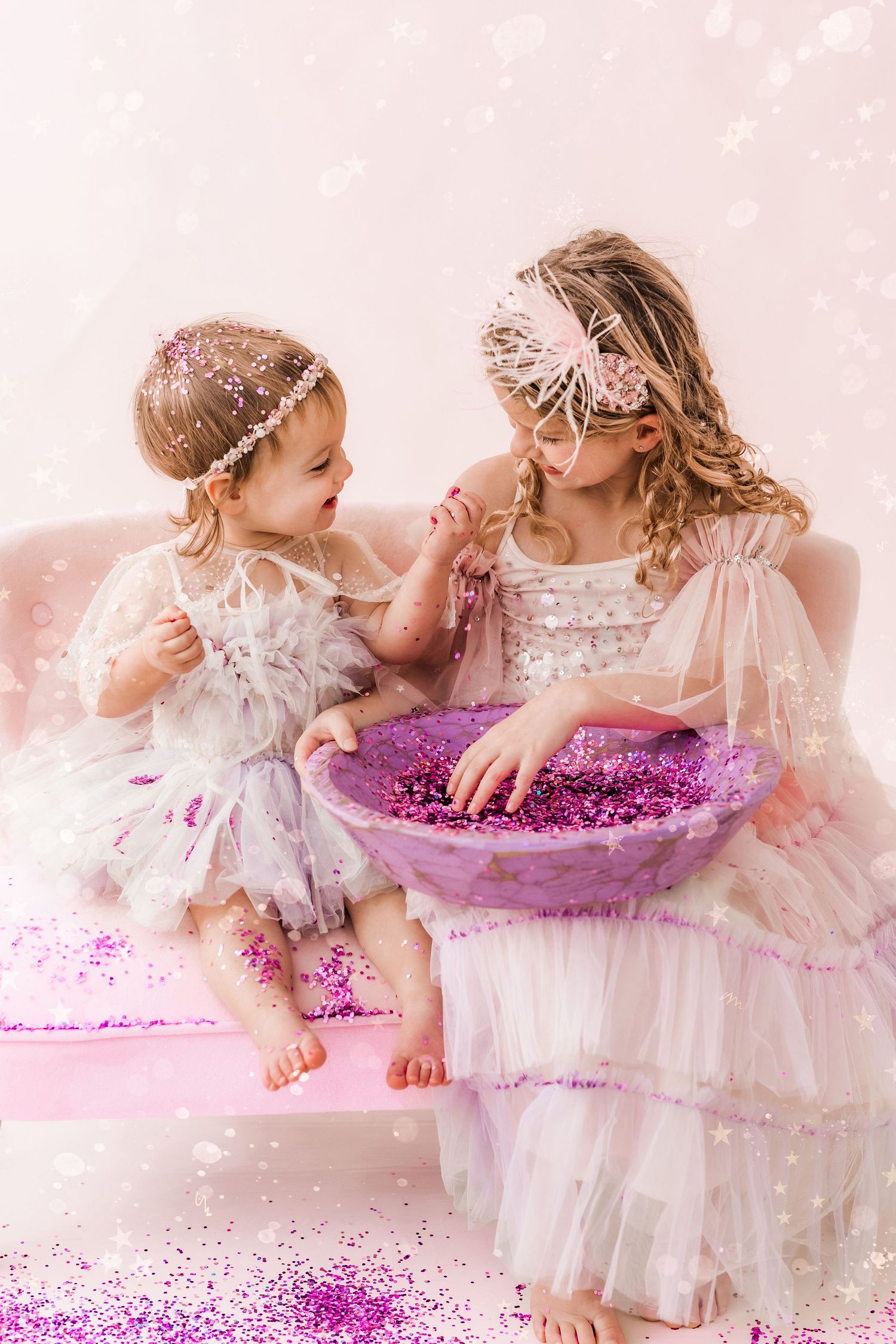 two sisters interacting together and smiling with a bowl of glitter