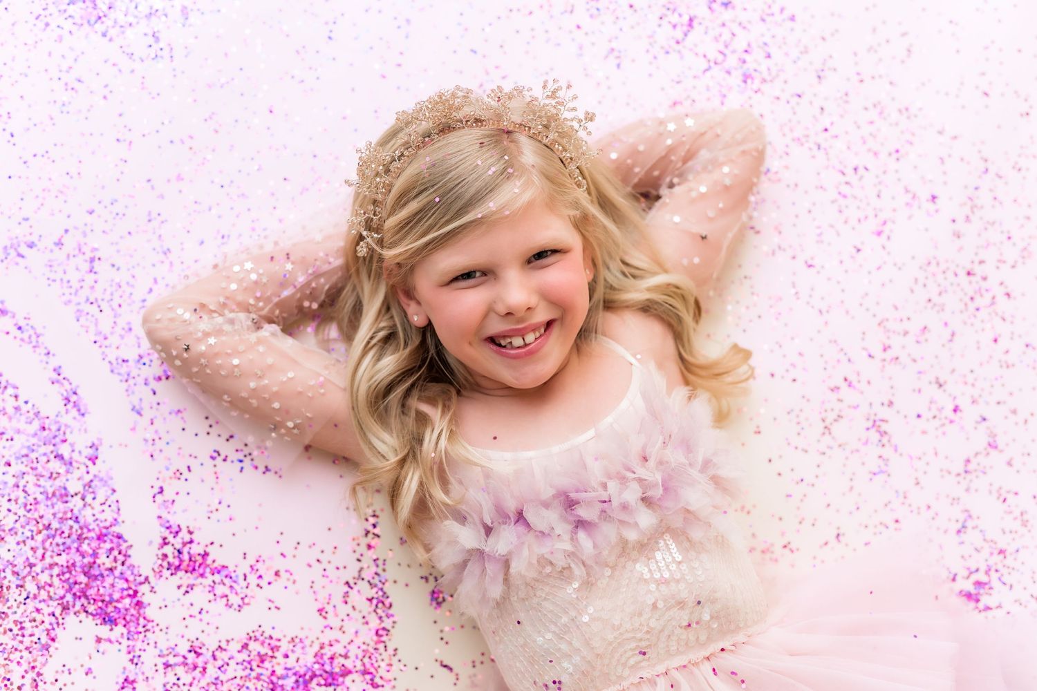 little girl laying down smiling with pink glitter