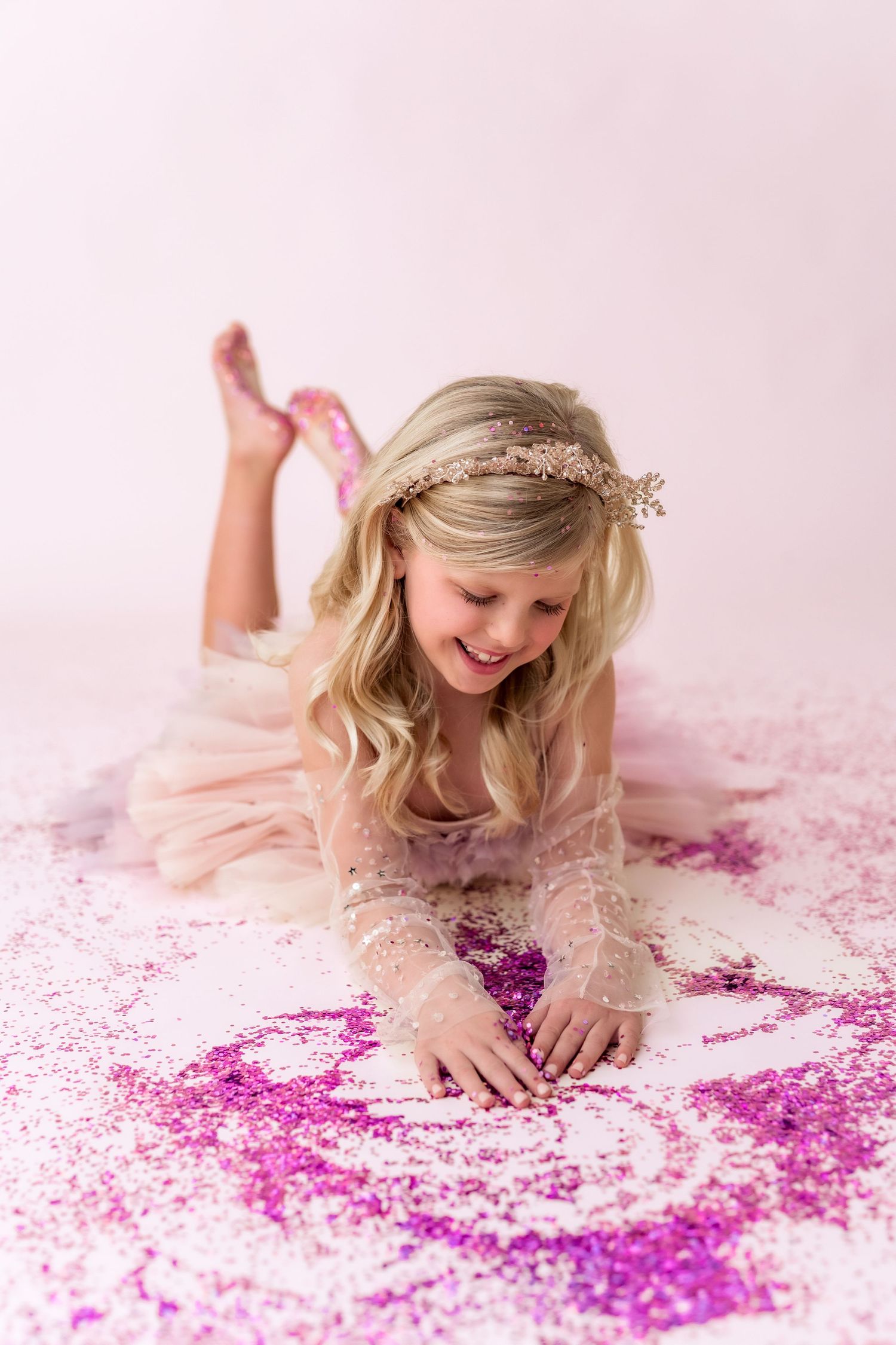 little girl in tiara playing with pink glitter