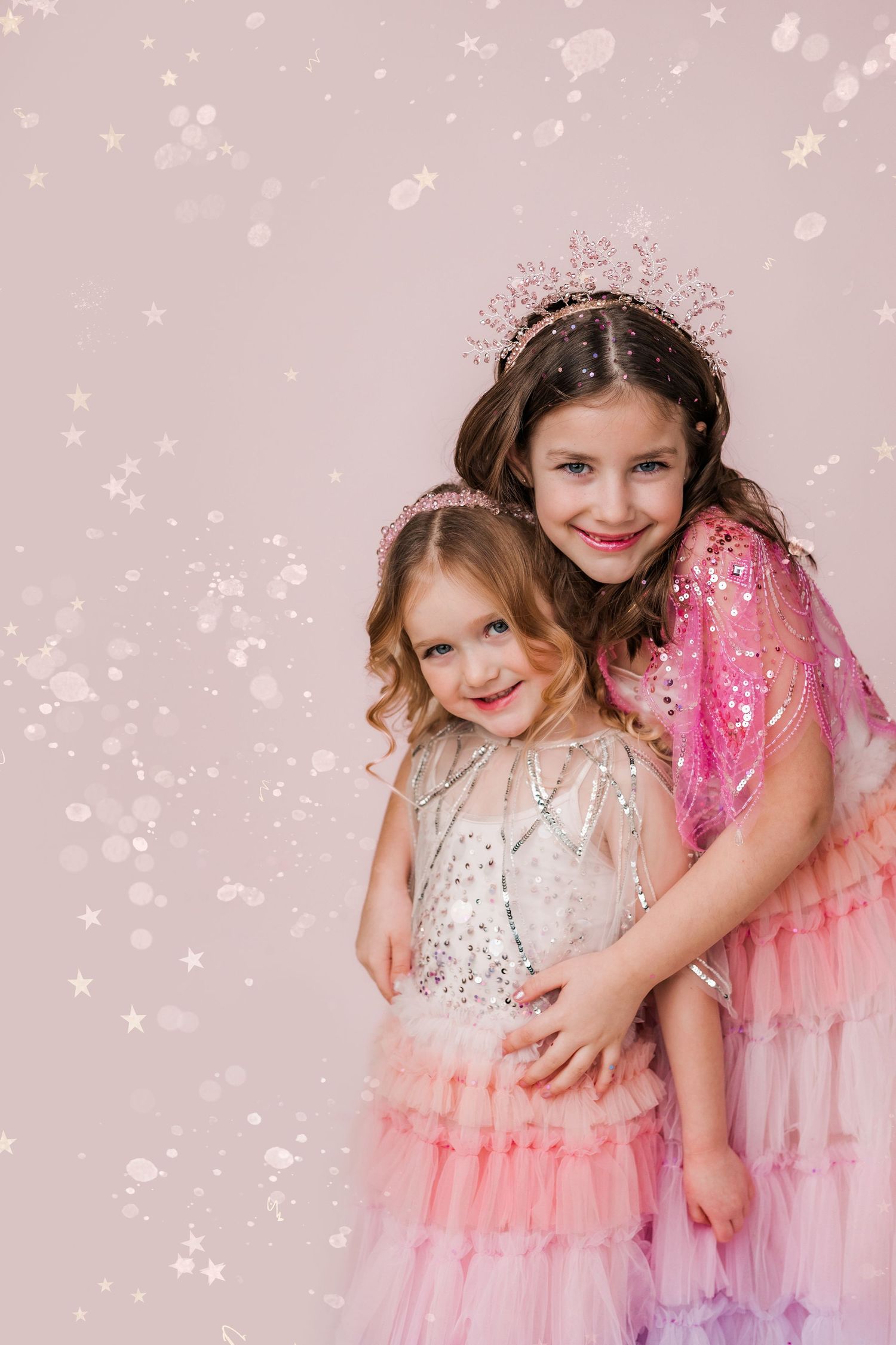 two little girls in princess dresses and tiaras hugging