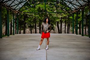 High school senior posing confidently outdoors with a natural smile, dressed in stylish attire