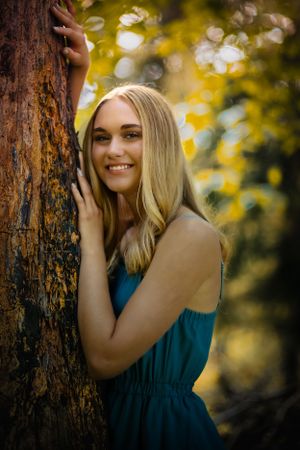 A girl leans on a tree. Vibrant colors encircle her