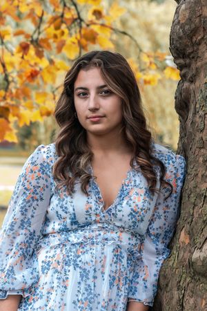 yellow and orange leaves provide a one of a kind background. The girl's blue dress stands out in contrast