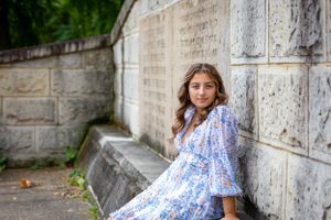 Stunning senior portrait with a textured stone wall behind a girl