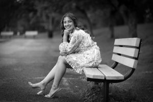 A black and white classic portrait of a girl poised and posed on a bench