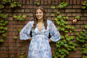 Wow, this background of red bricks and green ivy perfectly Frame this person who glances off camera with a huge smile