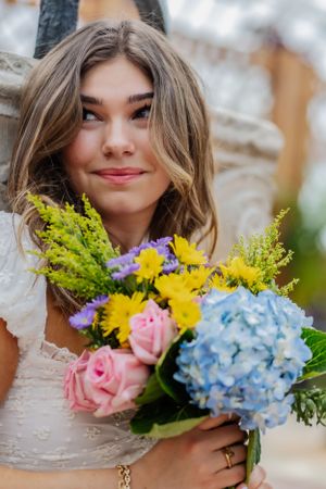 A magazine cover-like close-up featuring a girl holding a colorful bouquet of flowers