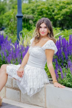 Feminine and classy, this sitting pose on stone with vibrant purple flowers is a guaranteed beautiful image
