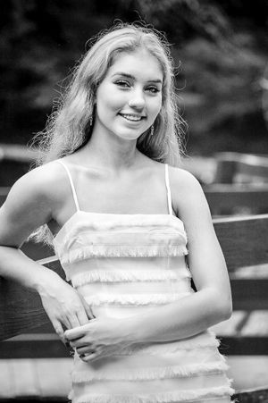 Classic and timeless senior portrait of a girl leaning delicately on a wooden fence