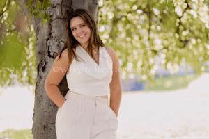 Casual and candid this image features a teenage senior girl leaning against a tree